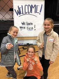 students smiling with "We love your face" sign